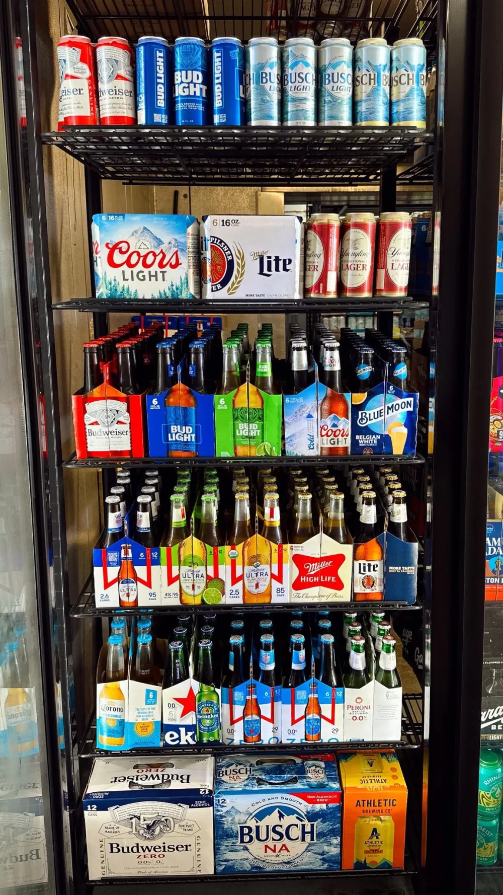 Cooler door stocked with domestic beer cans and bottles