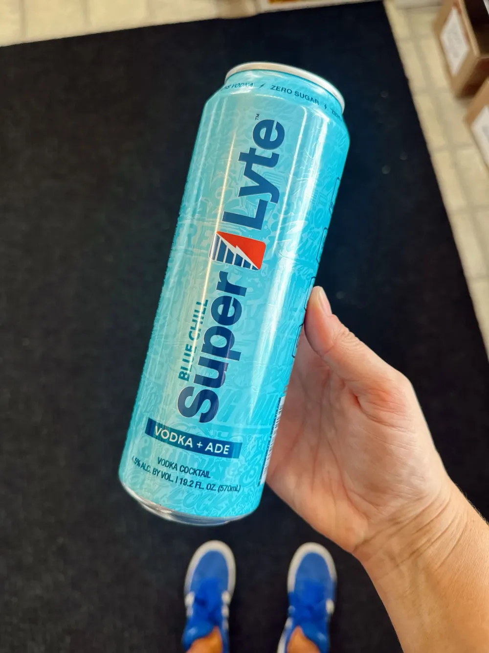 A hand holding a tall can of SuperLyte vodka-ade inside the store